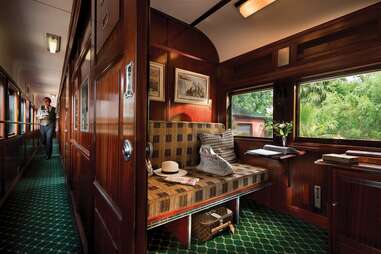 wood-paneled interior of a train in Africa, with views of greenery