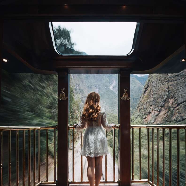 a woman standing on the back of a train looking out 