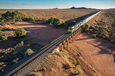 a train traveling through red sand outback in Australia