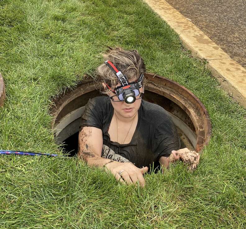 A volunteer goes down a man hole.