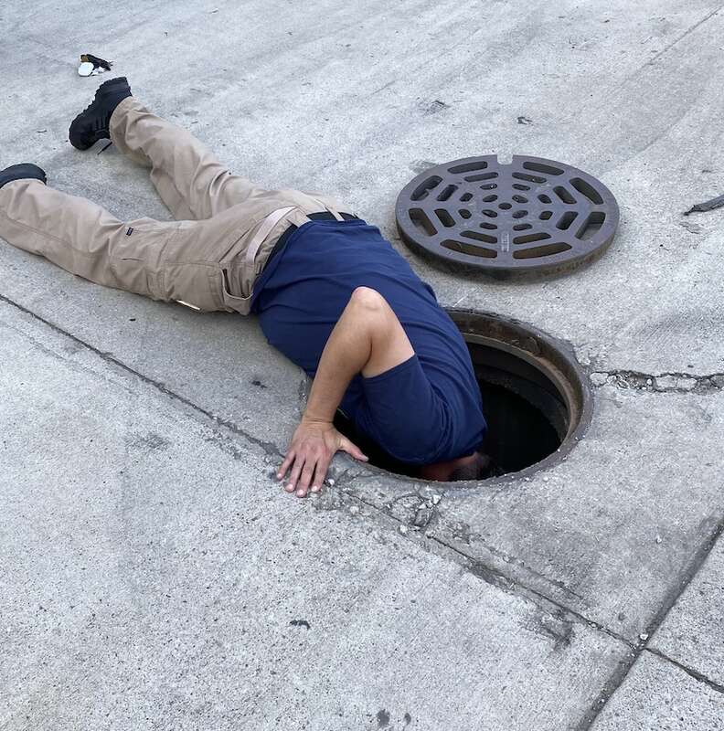 A man looks down a man hole.