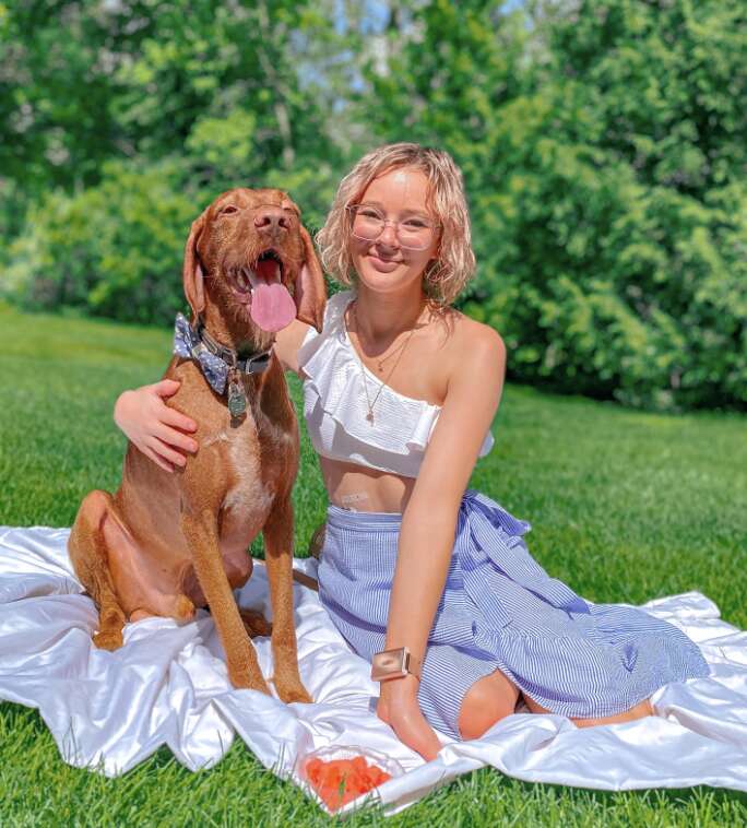 dog and woman sit in a park 