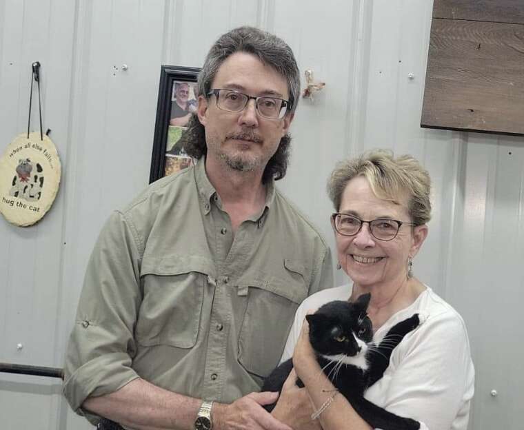 couple poses with black cat 