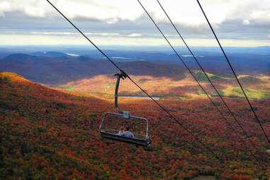 couple on ski lift hovering above fall foliage