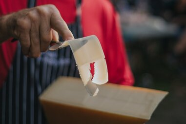 man scraping a block of cheese
