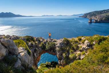 Tourist standing on the natural stone bridge near the sea