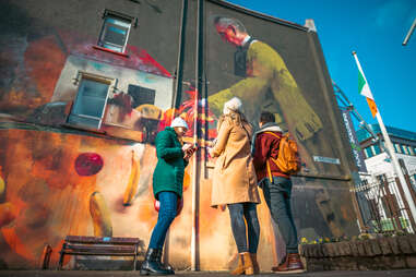 people standing next to mural