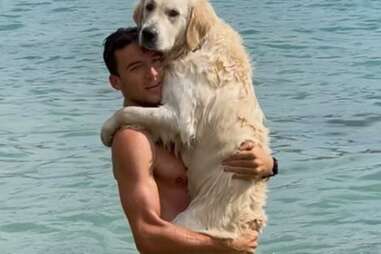 dog hugs man in water