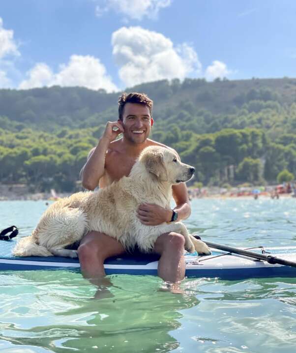 dog and man sit on surfboard
