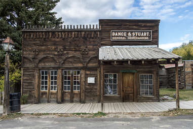 Empty Dirt Street In An Old Western Town With Various Wooden