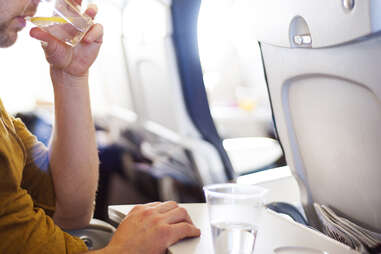 man on plane drinking from cup