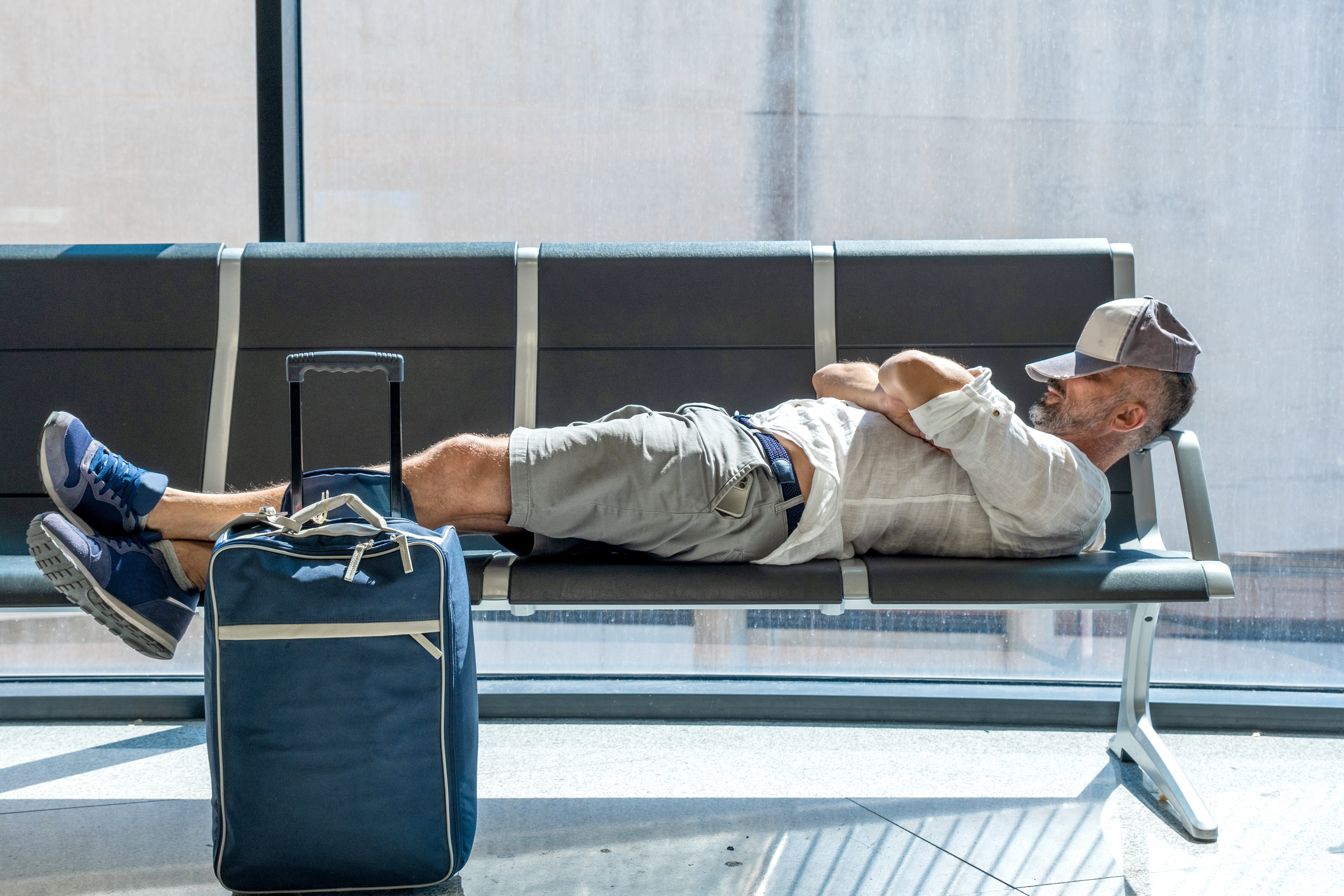man laying on airport seats