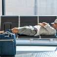 man laying on airport seats
