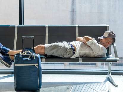 man laying on airport seats