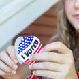 young woman peels I Voted sticker