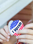 young woman peels I Voted sticker