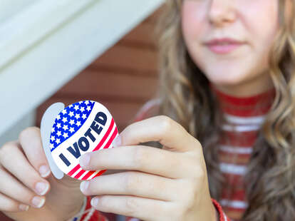 young woman peels I Voted sticker