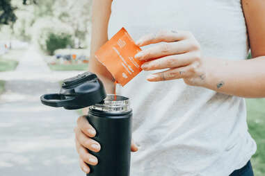 woman pouring health powder into bottle