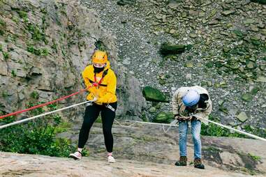 people rappelling down rock