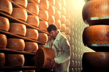 man holding large cheese wheel