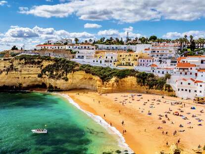 View of beach in Carvoeiro town with colorful houses on coast 