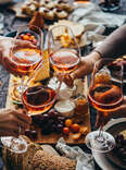 clinking of orange wine glasses at holiday dinner party 