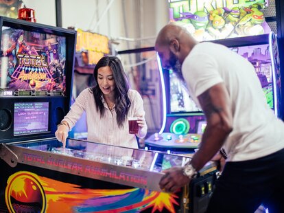 Two people playing pinball