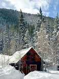 cabin in the snow in front of wooded mountains