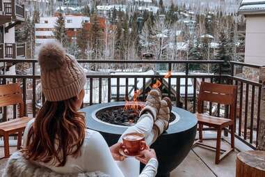 woman relaxing by fire pit near ski mountain