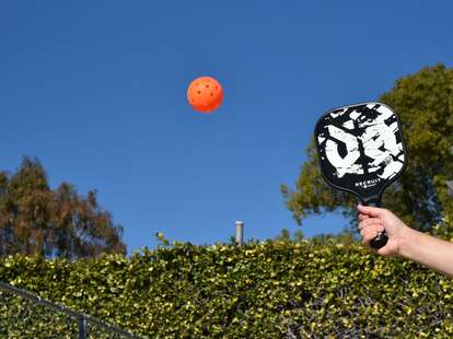 Pickleball paddle and ball in the air