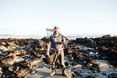 Spencer Marley holding net and basket on rocky beach