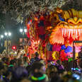 A colorful red and orange parade float in the crowded streets of New Orleans