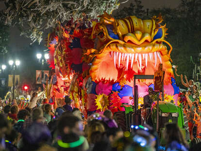 A colorful red and orange parade float in the crowded streets of New Orleans