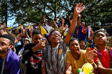 Crowd of people, including a young boy with glasses, enjoying the Mardi Gras Parade.