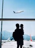 A father holds his child while watching a plane through the window at an airport as airlines revise their family seating policies
