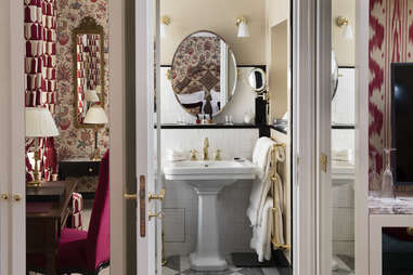 A sink in a richly decorated bathroom with gold fixtures and an antique mirror. 