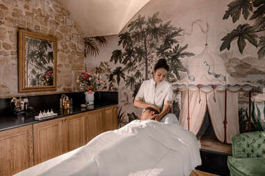 A spa room with a customer receiving a facial from a spa technician at Relais Christine's Guerlain Spa. 