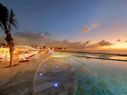 The pool deck sunset overlooking the ocean at the Riviera Maya property in Mexico. 