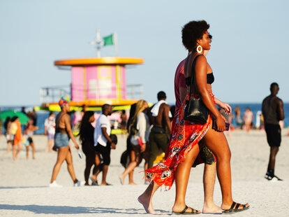 A young woman wearing a beach coverup walking along Miami Beach during Spring Break.