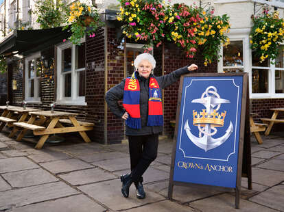Annette Badland as Mae from the show Ted Lasso, in front of the Crown & Anchor pub.