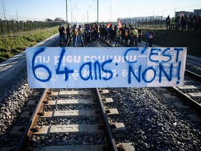 Protesters stand on the rail tracks behind a banner reading "64 years old, it's no" during an action called by the French union General Confederation of Labour 