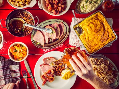Hand pouring syrup over loaded plate at Quebec sugar shack