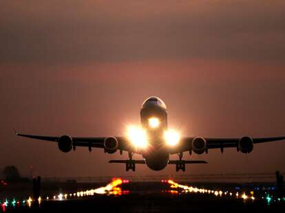 A plane taking off the runway at sunset.