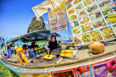 A vendor selling fresh food on a beach in the Krabi province in Thailand.