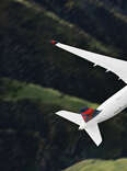 Delta plane flying over green mountains
