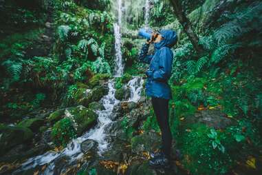 woman drinking from a grayl water bottle in the forest