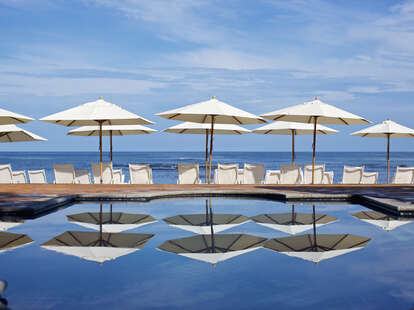 White beach umbrellas and lounge chairs at sunny ocean poolside