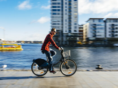 A young man at the Dublin, Ireland city dock riding a city bike