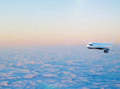 Airplane flying above the cloudscape at sunset