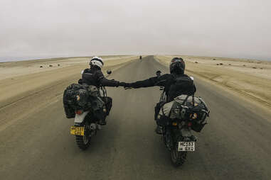 Motorcyclists holding hands while crossing desert in Namibia
